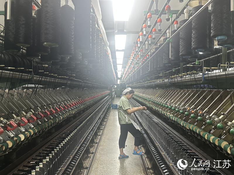 箭鹿集团纺织车间内,一名挡车工正在机器前巡检纱线。人民网 赵登岩摄