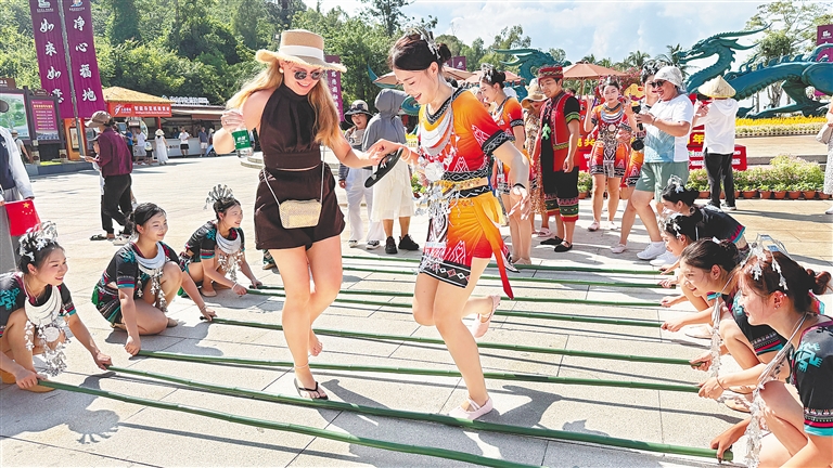 10月1日，外国游客在三亚南山文化旅游区体验非遗竹竿舞。新华社发